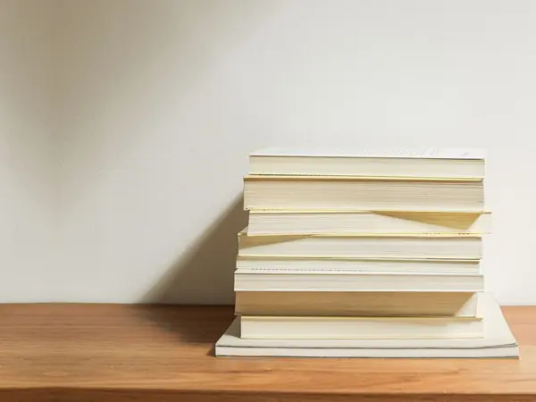 'n Netjiese stapel boeke op 'n houttafel